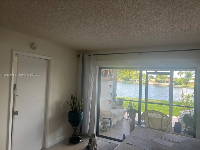 living room featuring a textured ceiling, light tile patterned floors, and a water view