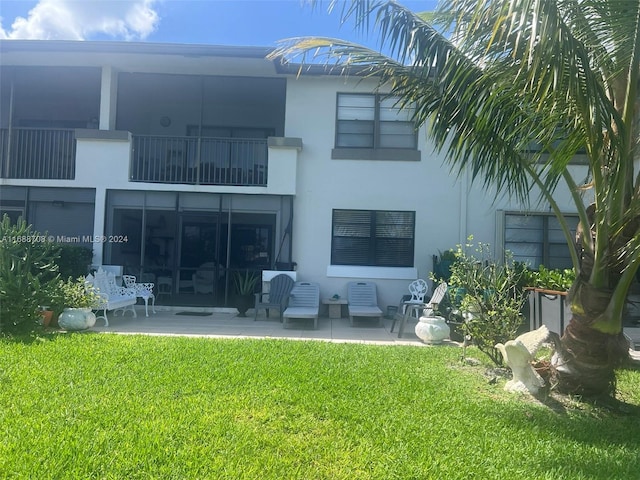 rear view of property featuring a balcony and a lawn