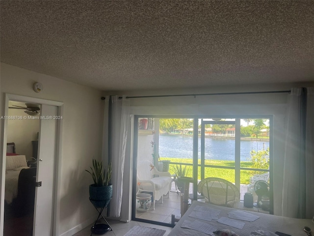 tiled bedroom with a water view, a textured ceiling, and multiple windows