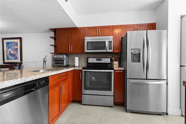 kitchen featuring decorative backsplash, light stone counters, a textured ceiling, stainless steel appliances, and sink