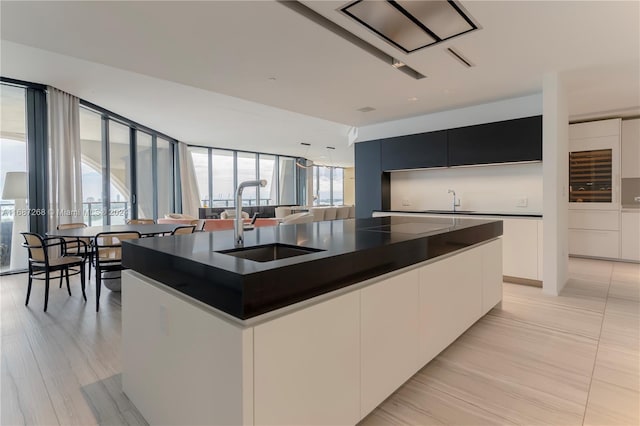 kitchen with white cabinetry, sink, and a center island with sink