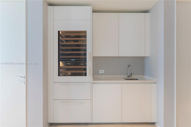 bar featuring wine cooler, sink, and white cabinets