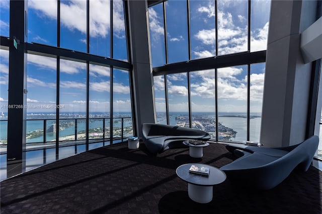 living room featuring a towering ceiling, a wall of windows, and a water view