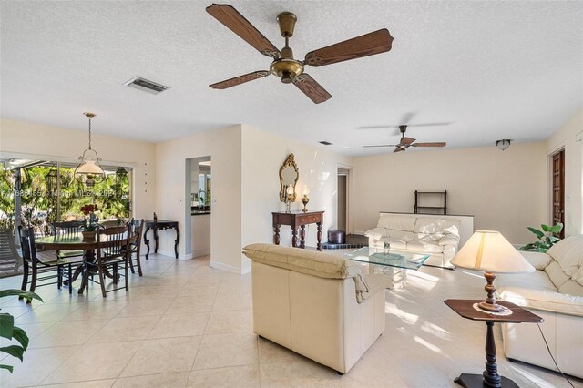 living room with light tile patterned flooring, a textured ceiling, and ceiling fan