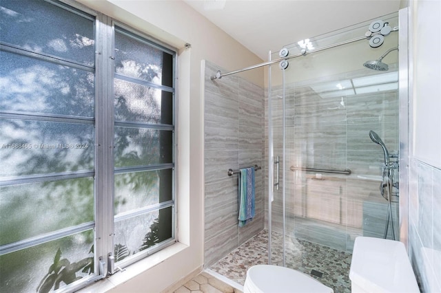 bathroom featuring walk in shower, tile patterned floors, and toilet