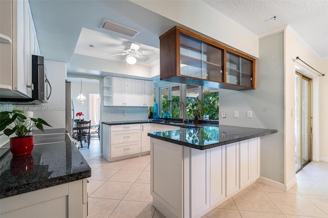 kitchen featuring white cabinetry, kitchen peninsula, a textured ceiling, and dark stone countertops