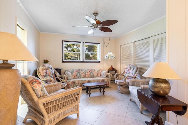 living room with ornamental molding, a textured ceiling, light tile patterned flooring, and ceiling fan