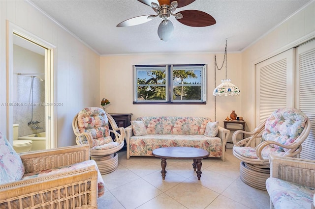 tiled living room with ceiling fan, a textured ceiling, and ornamental molding