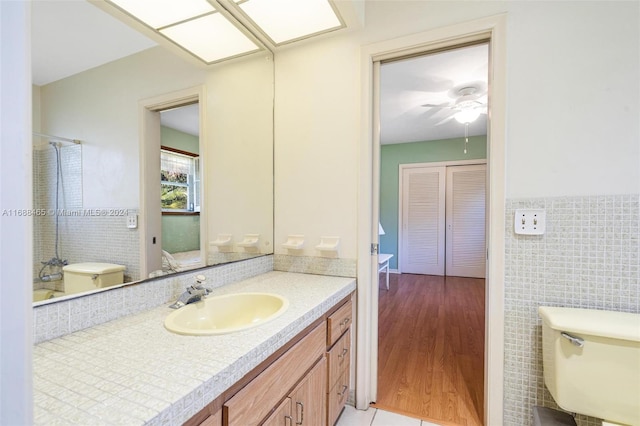 bathroom with toilet, vanity, tile walls, and wood-type flooring