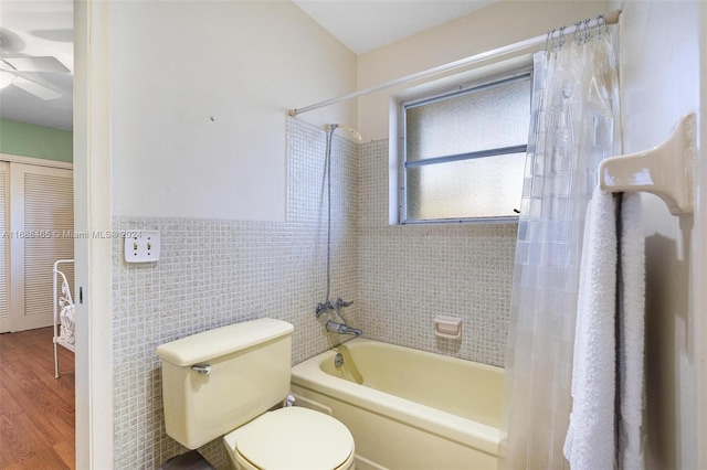 bathroom with toilet, tile walls, hardwood / wood-style floors, ceiling fan, and shower / tub combo with curtain