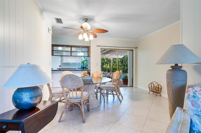 tiled dining area featuring wood walls, ceiling fan, a textured ceiling, and crown molding