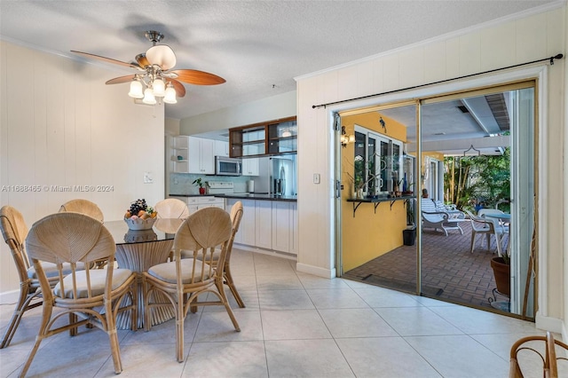 tiled dining room featuring ornamental molding, a textured ceiling, and ceiling fan