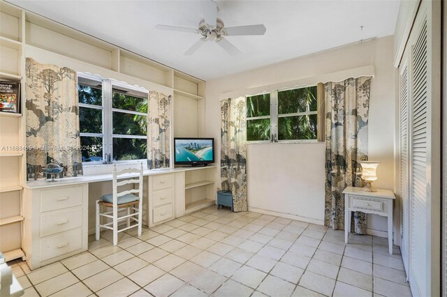 tiled home office with built in desk, ceiling fan, and plenty of natural light