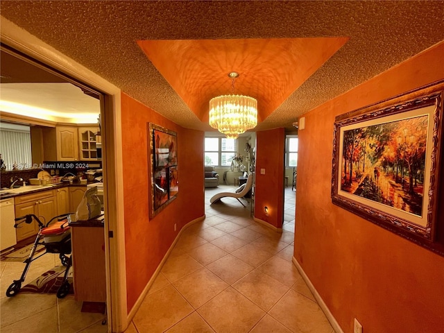 hallway with an inviting chandelier, sink, a textured ceiling, and light tile patterned flooring