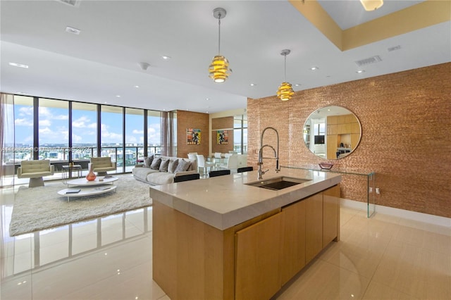 kitchen with light tile patterned flooring, a large island with sink, pendant lighting, and sink