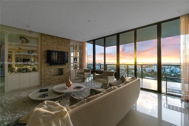 living room with built in shelves, a stone fireplace, a wall of windows, and tile patterned floors