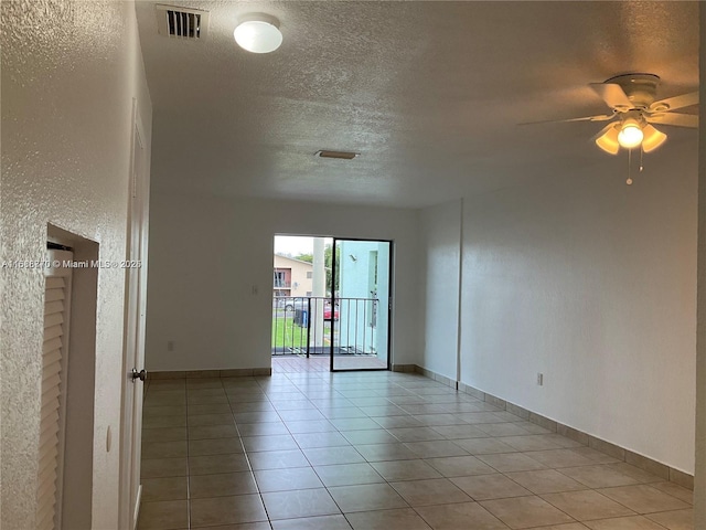 spare room with light tile patterned flooring, ceiling fan, and a textured ceiling