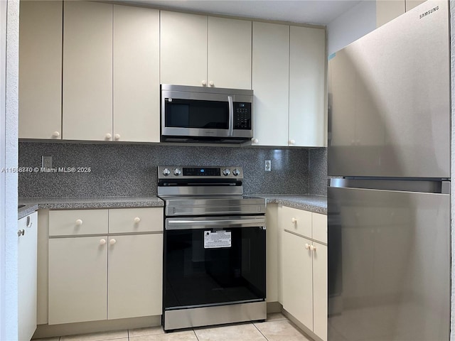 kitchen featuring appliances with stainless steel finishes, light tile patterned floors, and backsplash