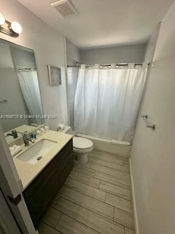 full bathroom with shower / bathtub combination with curtain, vanity, toilet, and wood-type flooring