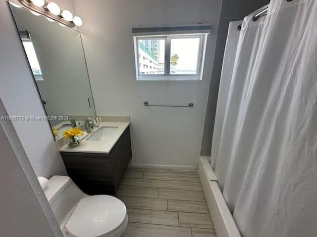 bathroom with hardwood / wood-style flooring, toilet, vanity, and a shower with shower curtain