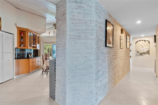 hall with light tile patterned flooring and brick wall