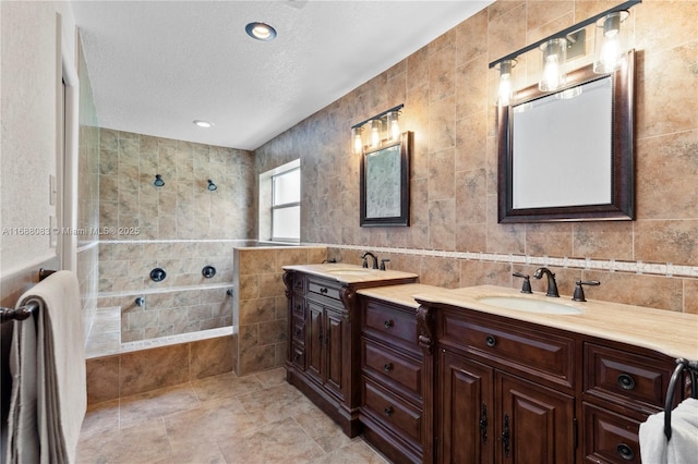 bathroom with vanity, a textured ceiling, tile walls, and walk in shower