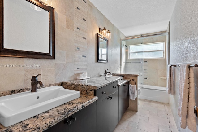 bathroom featuring tasteful backsplash, a textured ceiling, vanity, tile walls, and tiled shower / bath