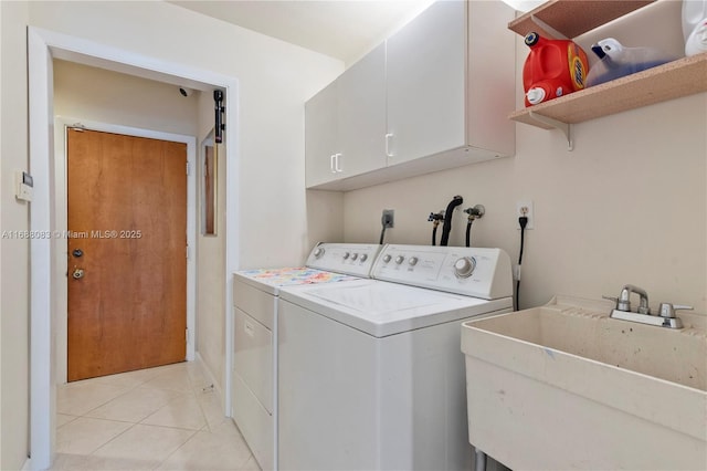 clothes washing area with sink, light tile patterned floors, cabinets, and independent washer and dryer