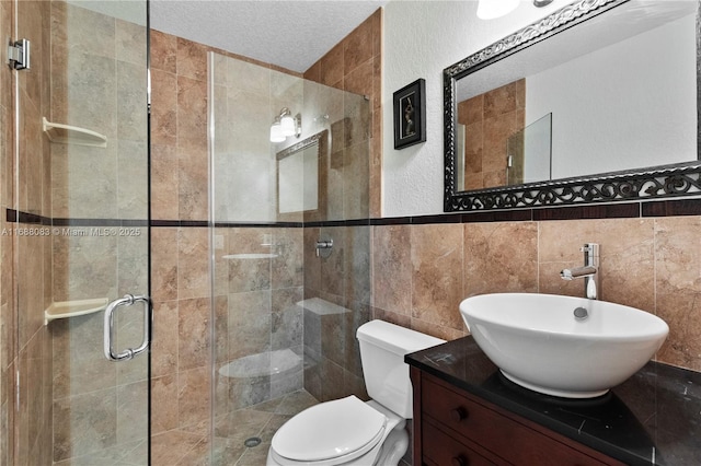 bathroom featuring walk in shower, a textured ceiling, toilet, vanity, and tile walls