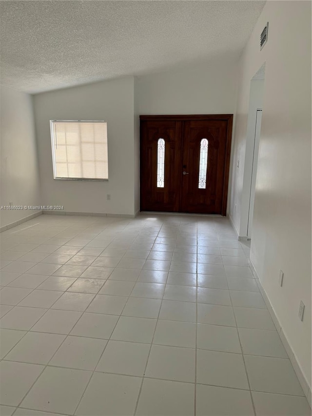 tiled entryway with lofted ceiling and a textured ceiling