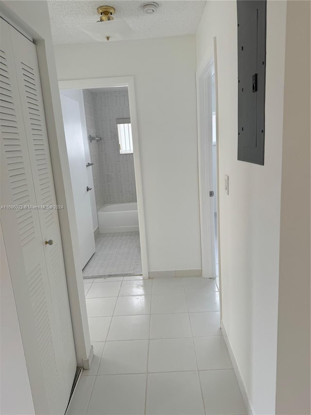 hall featuring electric panel, a textured ceiling, and light tile patterned floors