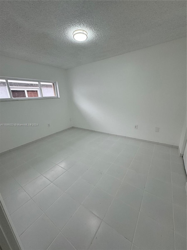 tiled empty room with a textured ceiling