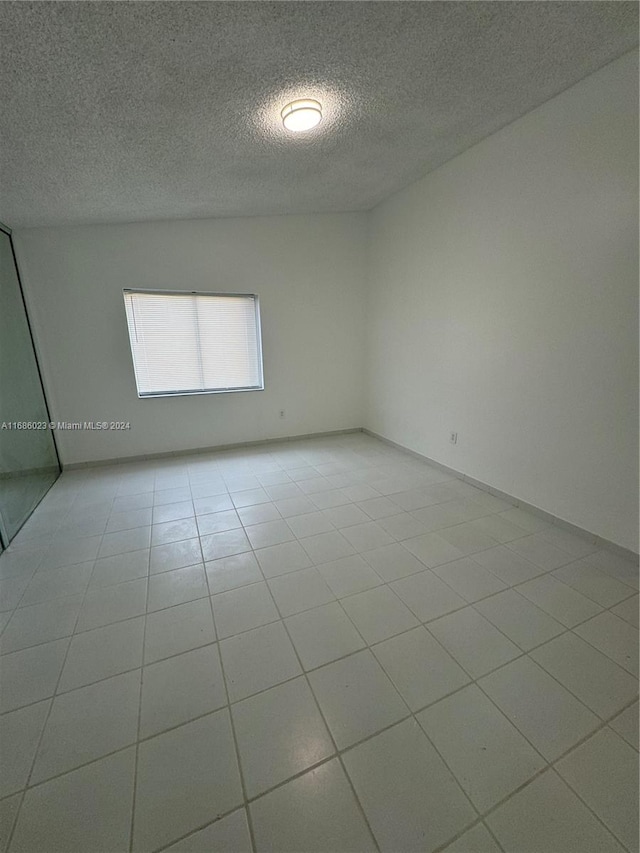 spare room with a textured ceiling and light tile patterned flooring