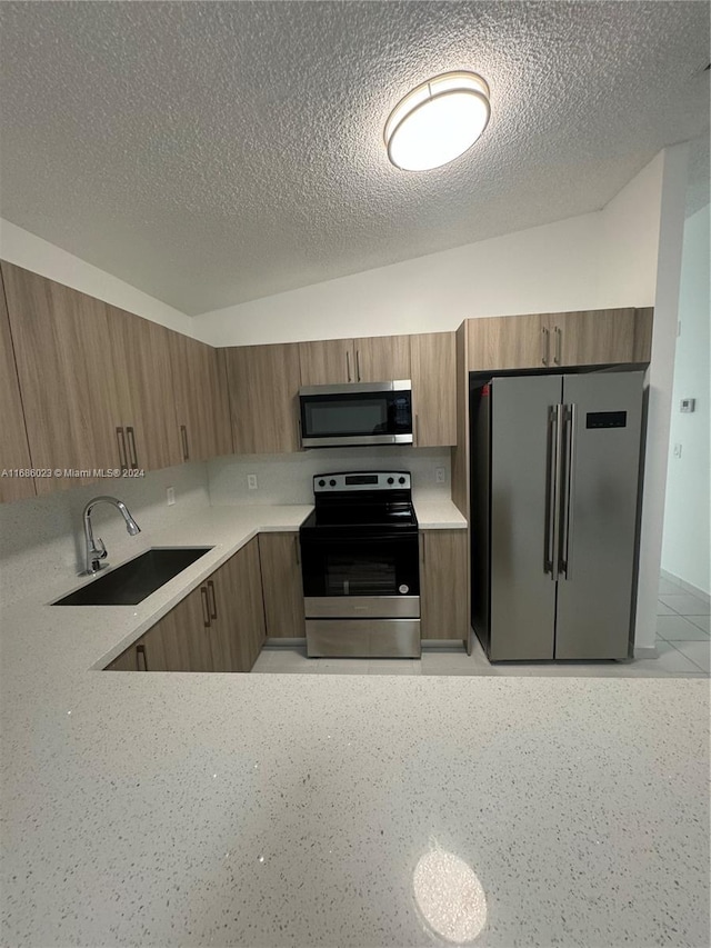 kitchen with stainless steel appliances, a textured ceiling, and sink