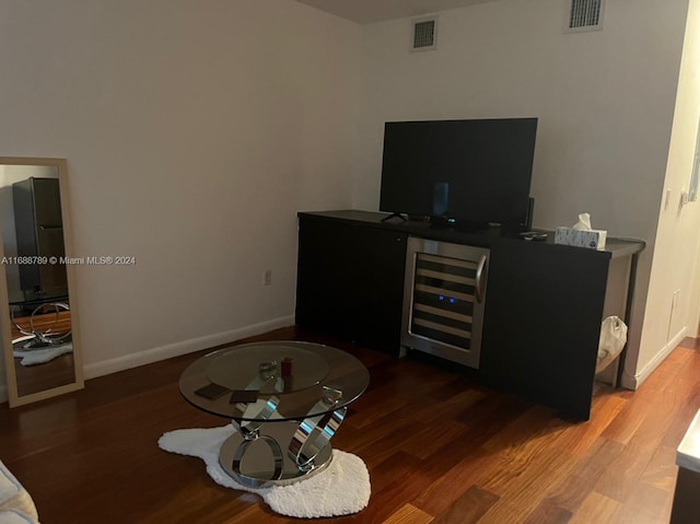 living room featuring wood-type flooring, beverage cooler, and indoor bar