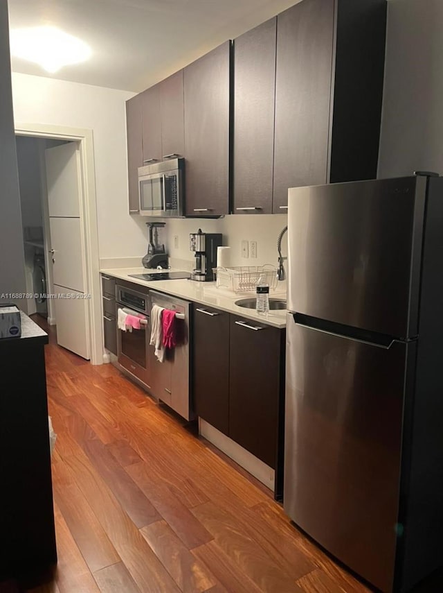 kitchen with sink, stainless steel appliances, and light wood-type flooring