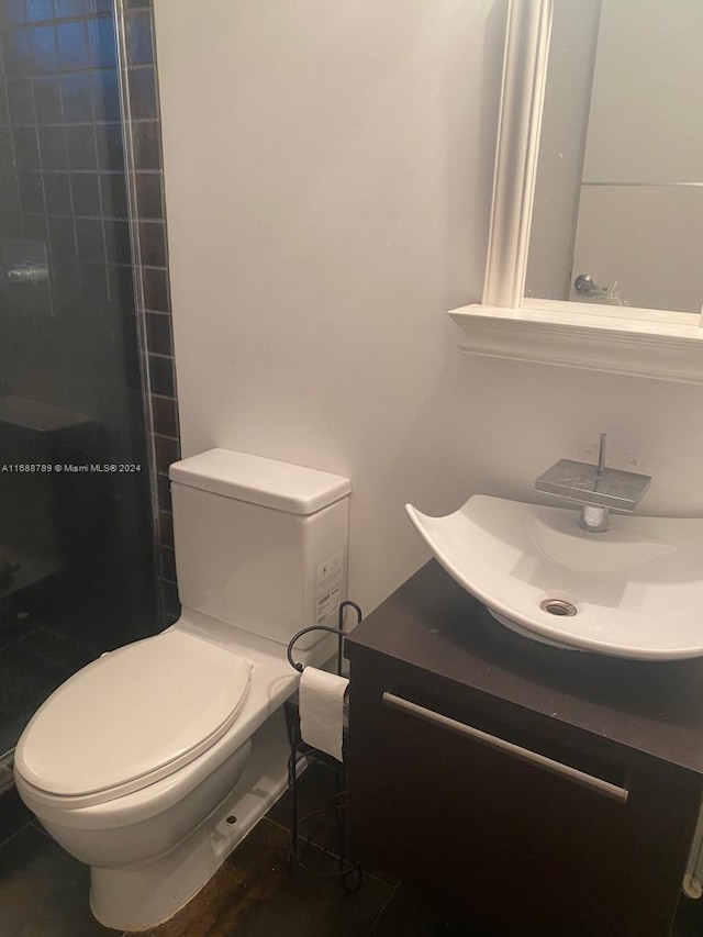 bathroom with tile patterned flooring, vanity, toilet, and walk in shower