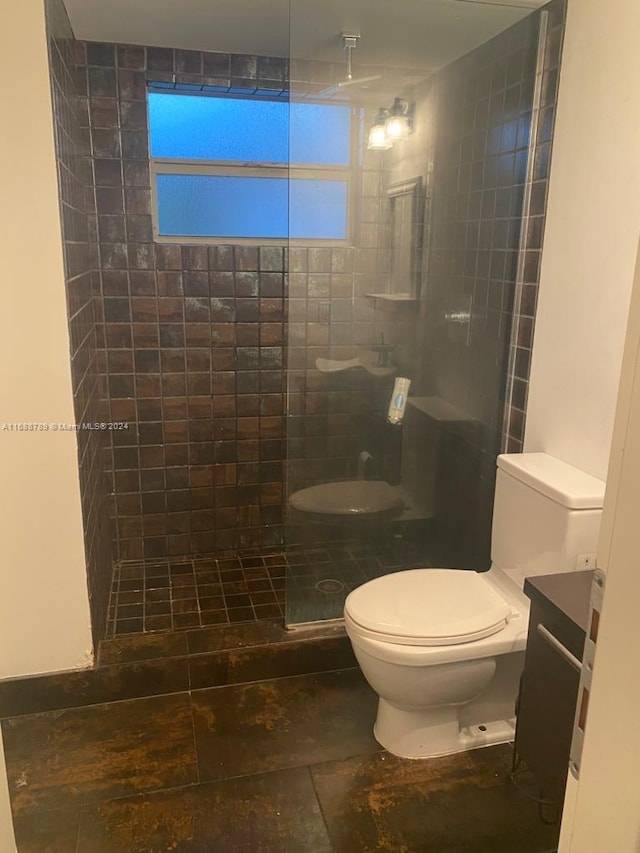 bathroom featuring a tile shower, vanity, and toilet