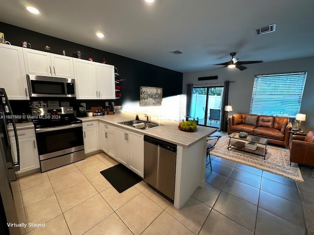 kitchen featuring sink, kitchen peninsula, appliances with stainless steel finishes, ceiling fan, and white cabinets