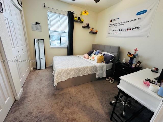 carpeted bedroom featuring ceiling fan and a closet