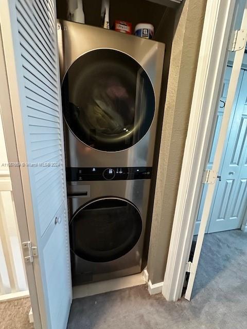 washroom with stacked washer and dryer and carpet