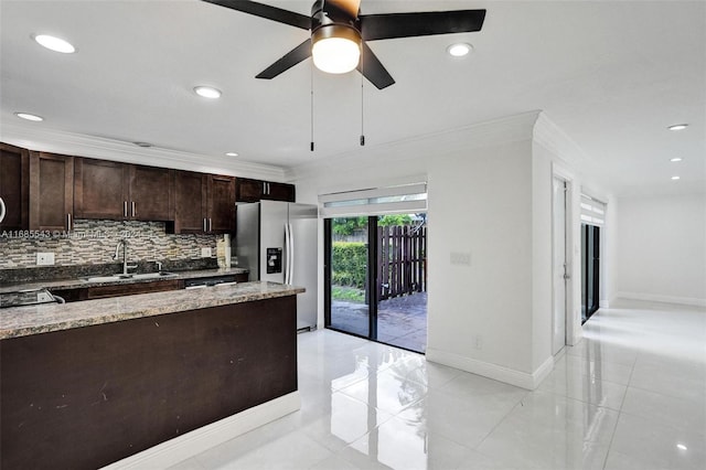 kitchen with stainless steel refrigerator with ice dispenser, dark brown cabinetry, sink, crown molding, and backsplash