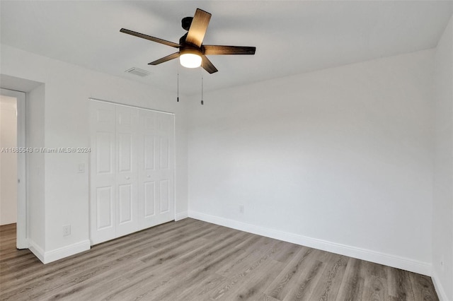 unfurnished bedroom featuring light hardwood / wood-style floors, ceiling fan, and a closet