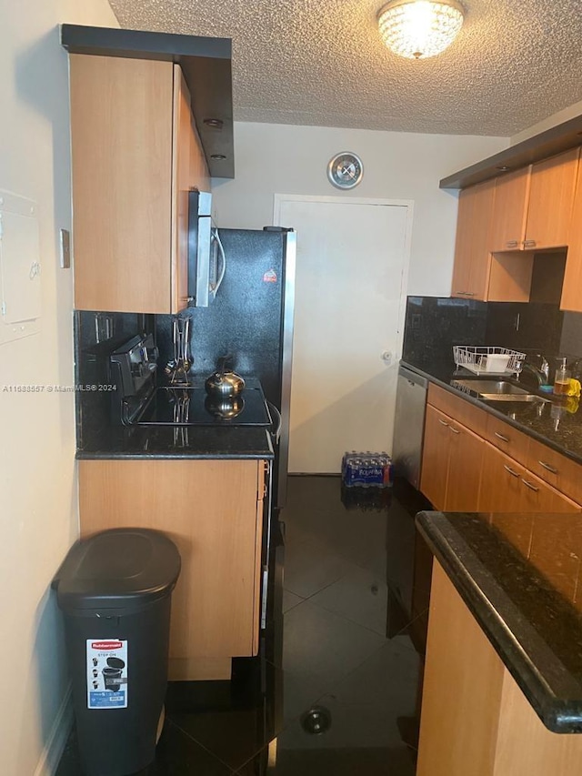 5401 Collins Ave Unit 412, Miami Beach, FL 33140 - kitchen with appliances with stainless steel finishes, tasteful backsplash, dark countertops, a textured ceiling, and tile patterned flooring