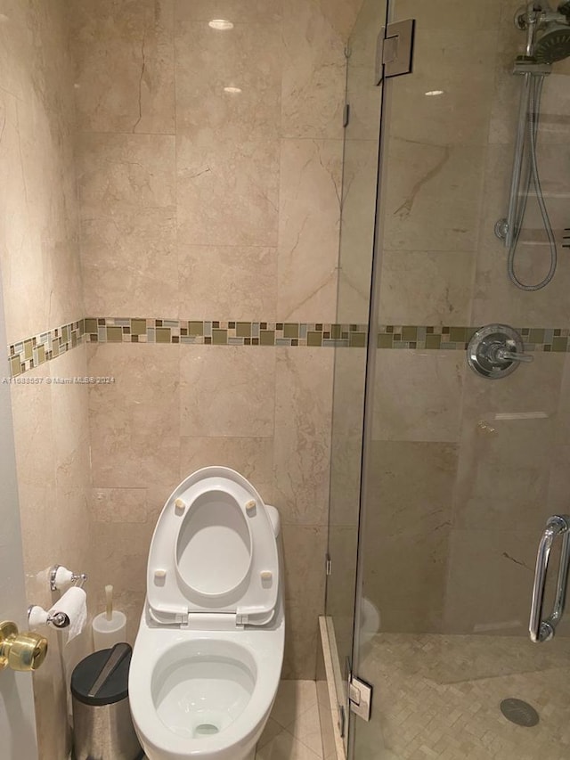 bathroom featuring toilet and a shower with shower door