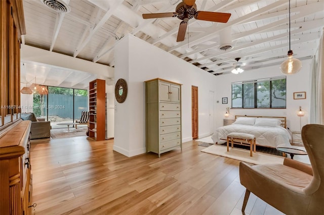 bedroom featuring ceiling fan, multiple windows, light hardwood / wood-style floors, and beam ceiling