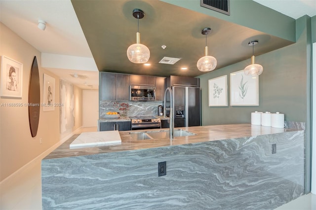 kitchen featuring stainless steel appliances, kitchen peninsula, tasteful backsplash, wood-type flooring, and pendant lighting