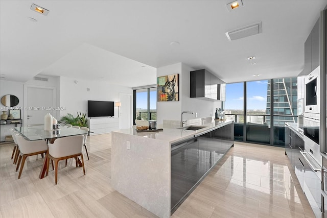 1451 Brickell Ave Unit 2205, Miami, FL 33131 - kitchen with expansive windows, open floor plan, a center island with sink, modern cabinets, and light tile patterned flooring