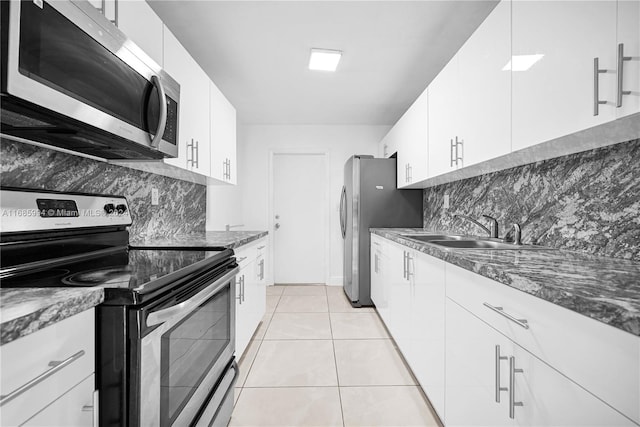 kitchen featuring white cabinets, light tile patterned flooring, sink, and appliances with stainless steel finishes