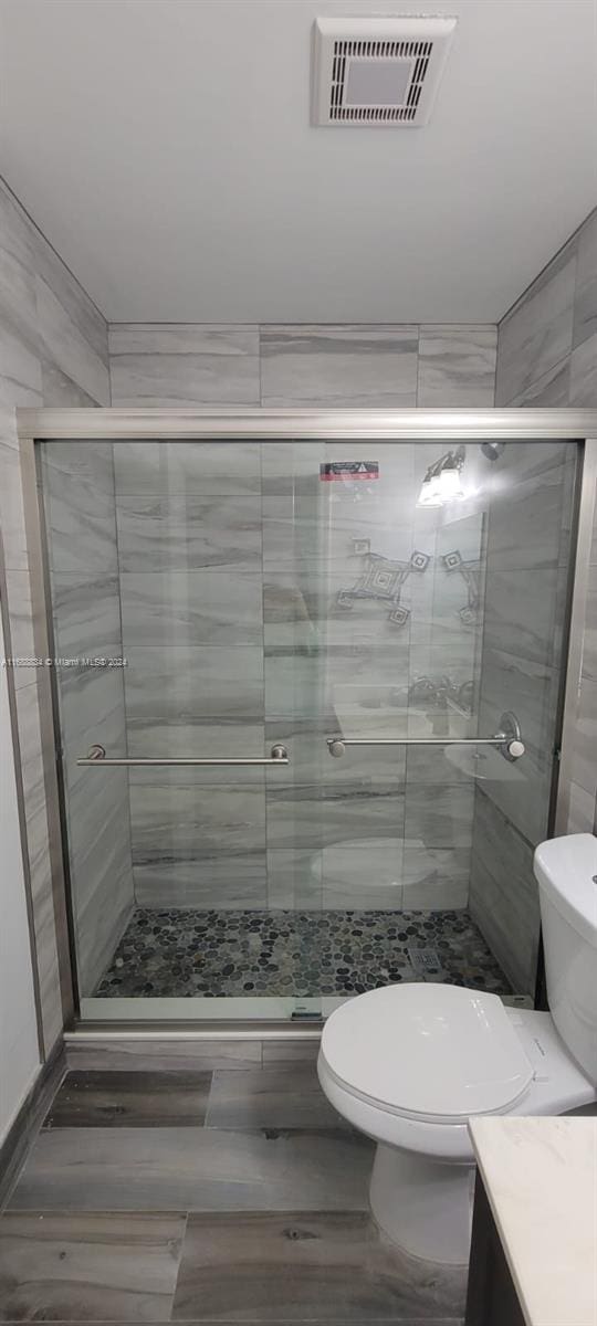 bathroom with walk in shower, vanity, and toilet